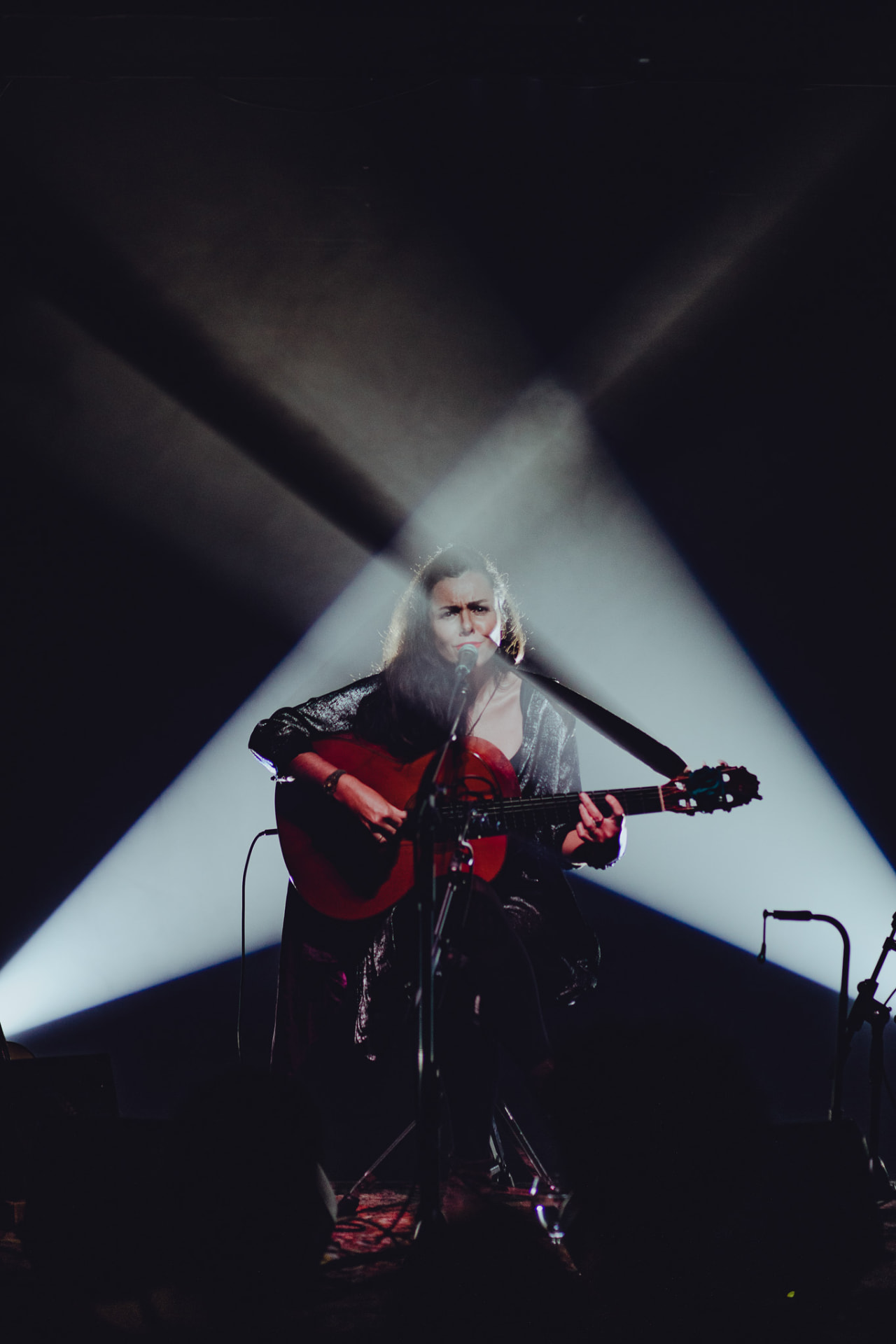 Carolina Zingler em palco entre dois feixes de luz cruzados