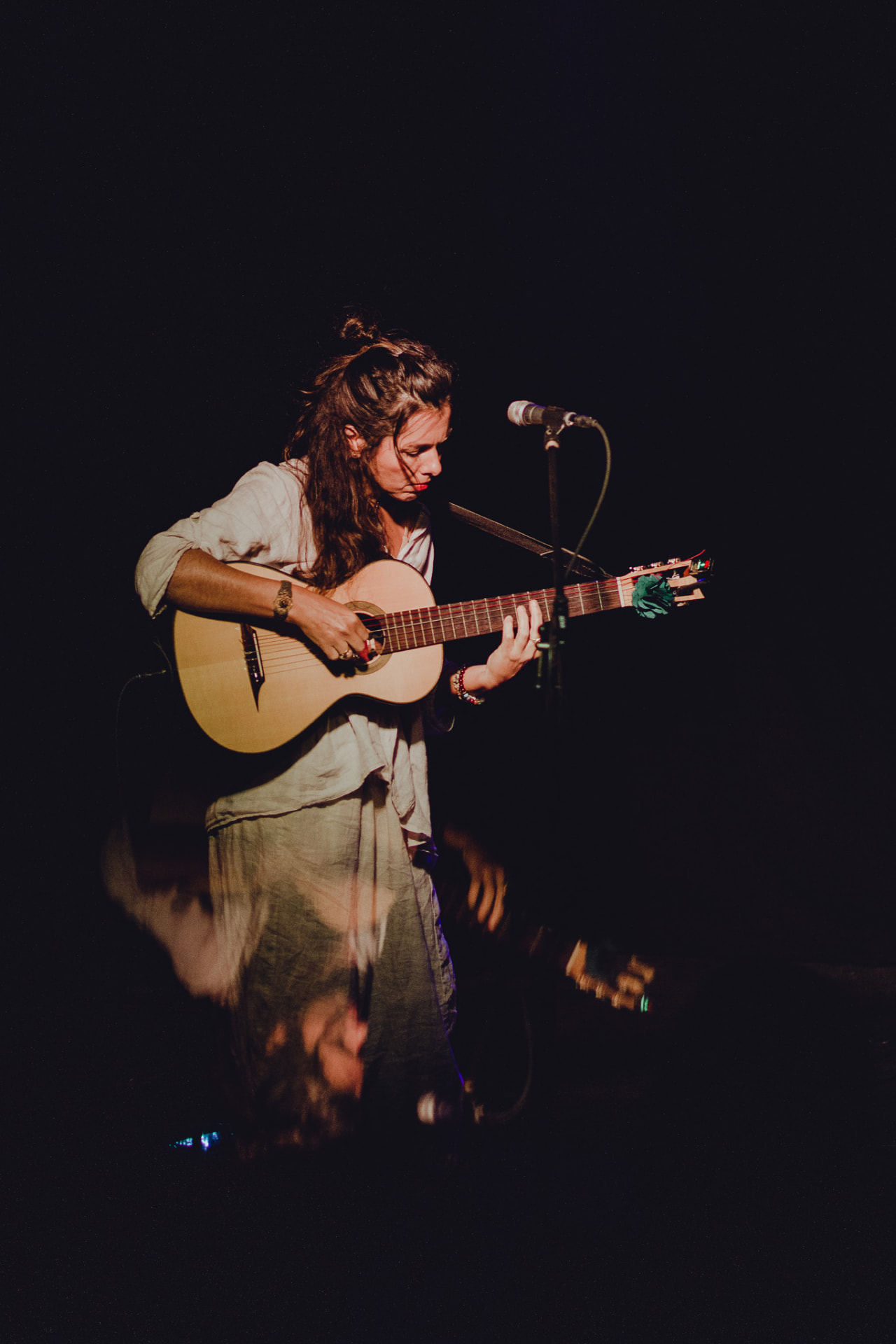 Carolina Zingler a tocar violão em palco, luz baixa